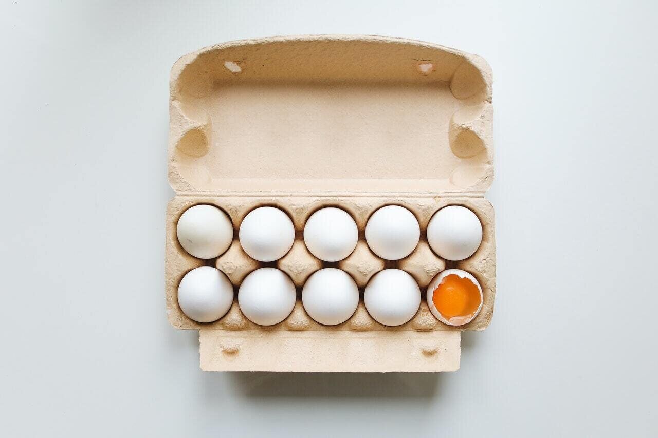 Eggs in a Carton. One Egg is Broken.