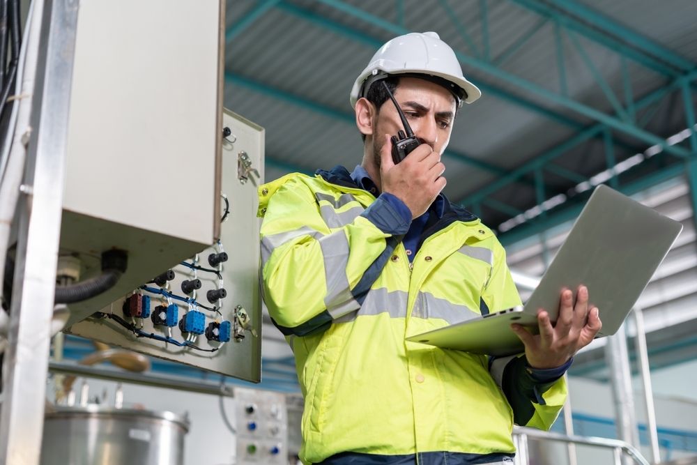 safety engineer speaking with someone on a walkie-talkie on the plant floor