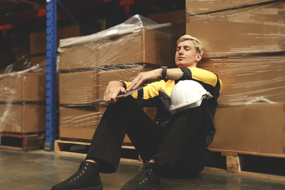 male worker seated on plant floor taking a break
